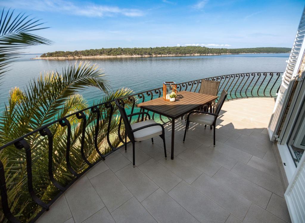 einen Tisch und Stühle auf einem Balkon mit Blick auf das Wasser in der Unterkunft Apartment Julietta in Rab