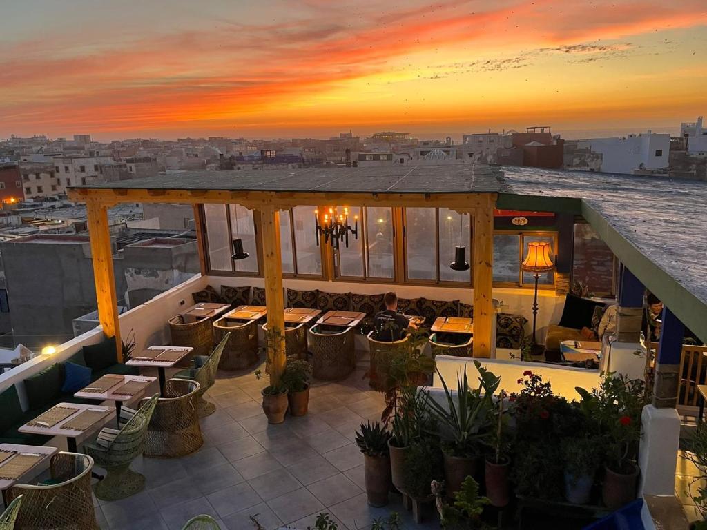 un patio all'ultimo piano con tavoli e sedie al tramonto di Atlantic Hostel a Essaouira