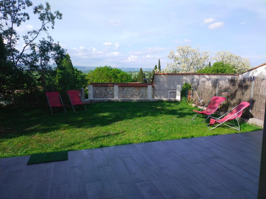 einen Hof mit zwei roten Stühlen und einem Zaun in der Unterkunft Maison de village in Lasbordes