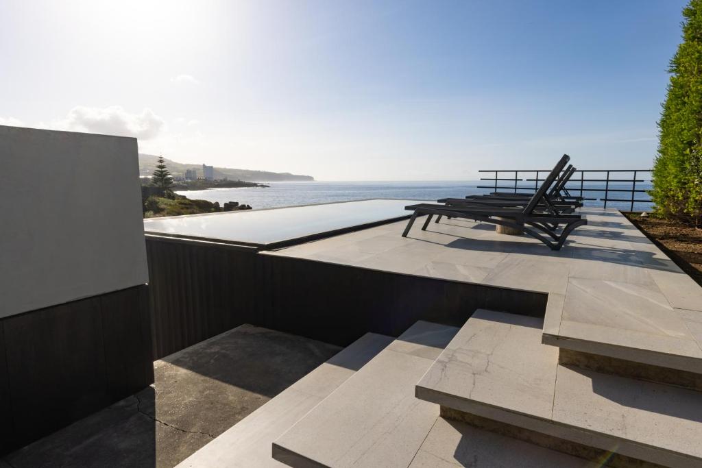a patio with a bench and a view of the ocean at Casa da Rocha by White Exclusive Suites & Villas in Lagoa