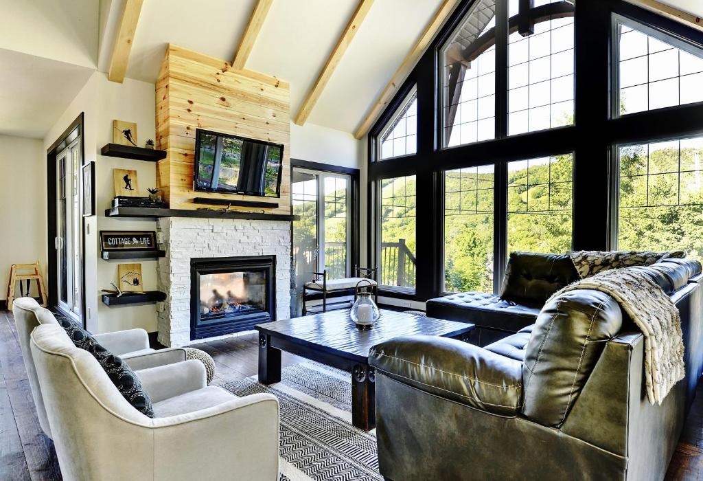 Una sala de estar con muebles de cuero y chimenea. en Chalets Alpins -13 Chemin des Skieurs, en Stoneham