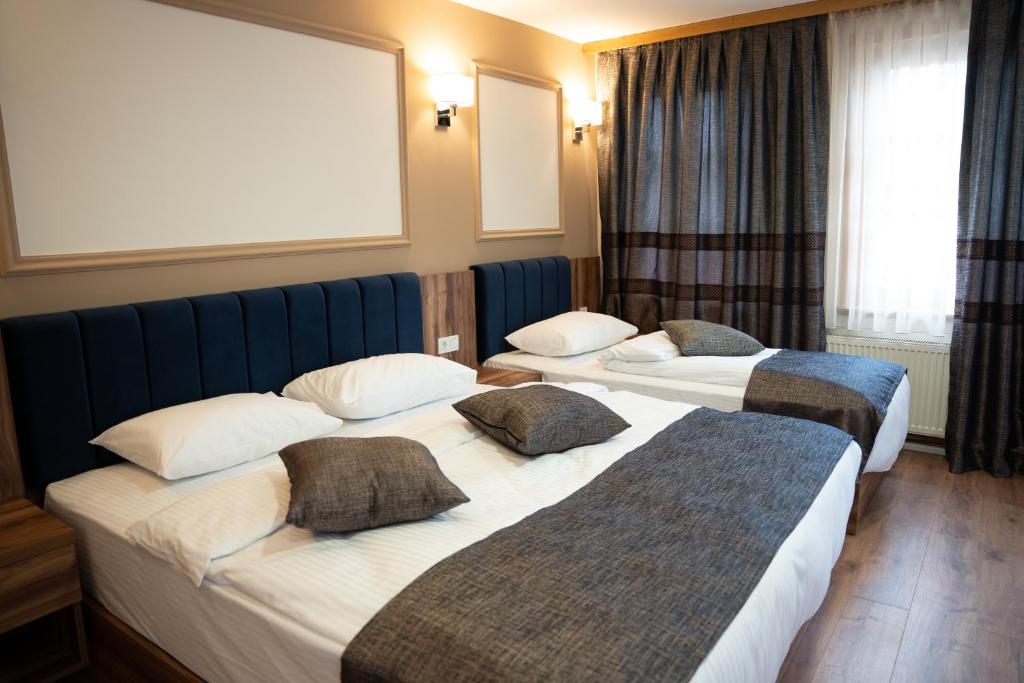 een hotelkamer met 2 bedden en een raam bij Amber Hotel in Sarajevo