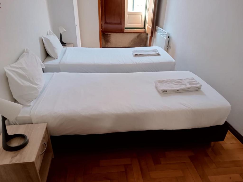 twee bedden in een kleine kamer met een raam bij Flores Apartment in Porto