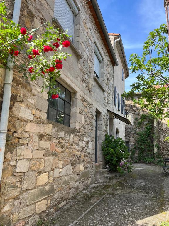 ein Steingebäude mit einem Fenster mit roten Blumen darauf in der Unterkunft Maison de village Cevenole climatisée à Branoux-Les-Taillades - Gard - #TravellerAwards 2024 in Branoux-les-Taillades
