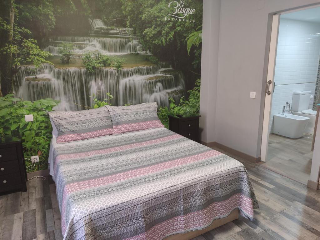 1 dormitorio con 1 cama y un mural con cascada en Hostal El Bosque Encantado Toledo, en Toledo