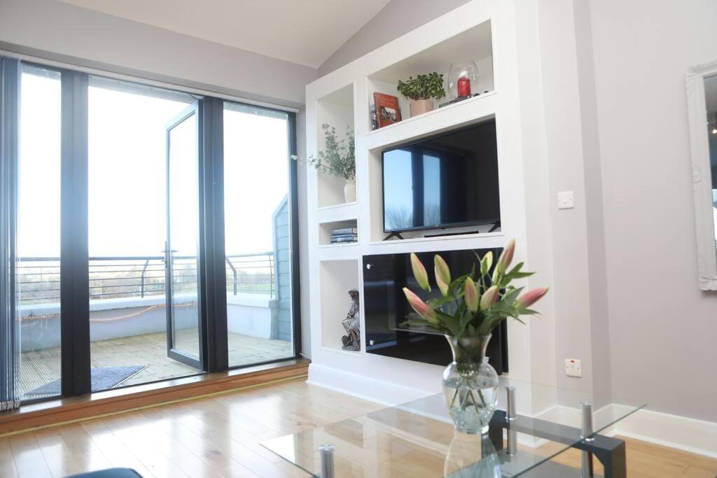 a living room with a television and a vase of flowers at Luxury Three Bedroom Apartment Foxford County Mayo in Foxford
