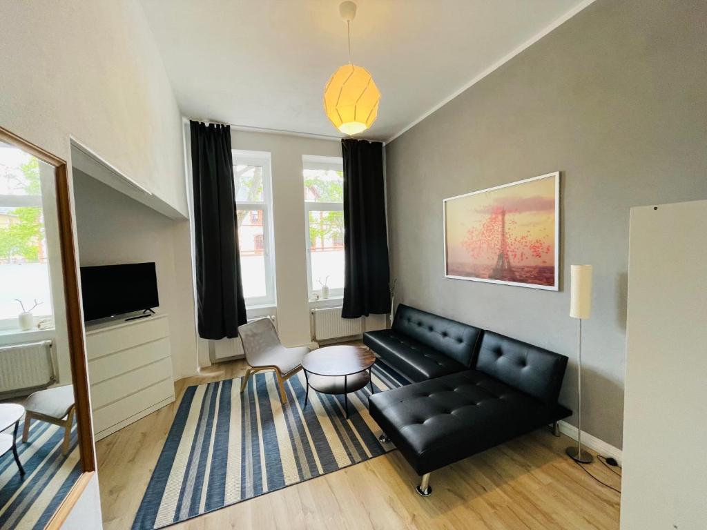 a living room with a black couch and a tv at Gemütliches Appartement "Nina" in Halle in Rusches Hof