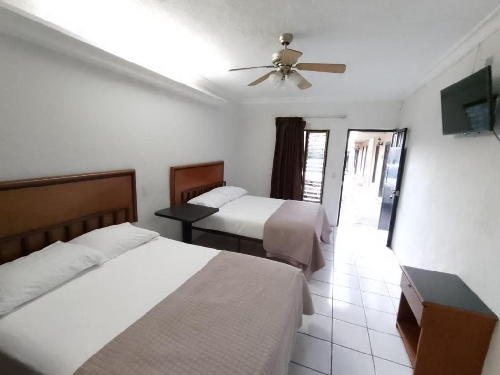 um quarto de hotel com 2 camas e uma ventoinha de tecto em Hotel Abasolo em Tequila