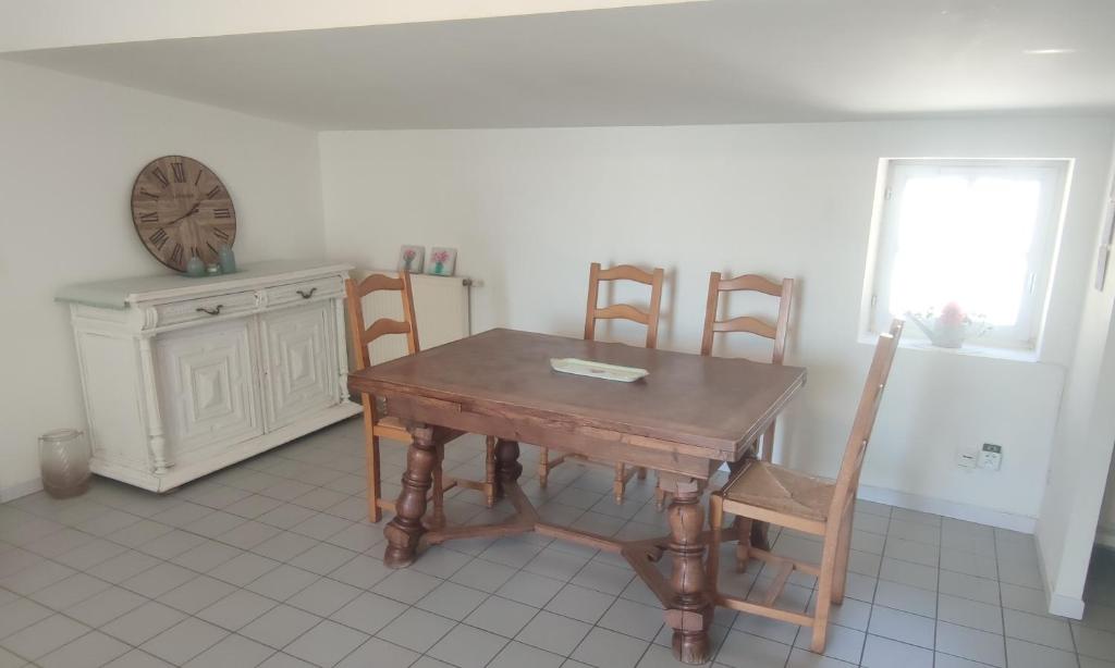 stół i krzesła w pokoju z zegarem w obiekcie T3 avec sa terrasse au cœur du village médiéval w mieście Sauzet