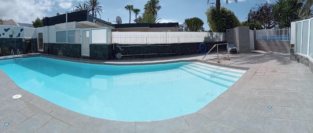 a large blue swimming pool in front of a house at Granada playa! in Maspalomas