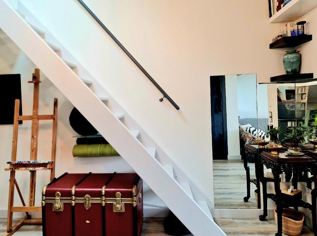 a room with a staircase with a suitcase and a table at Studio mezzanine entier à 5min de la plage et de St tropez in Cogolin