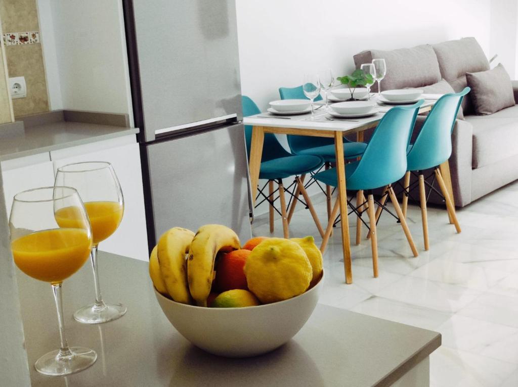 un bol de fruta en una mesa con dos copas de vino en Garu Apartamentos en Fuengirola