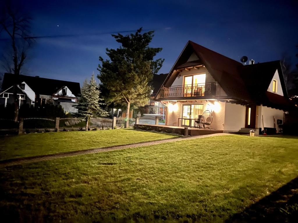 a house with a lawn in front of it at night at Domek Skała in Kościelisko