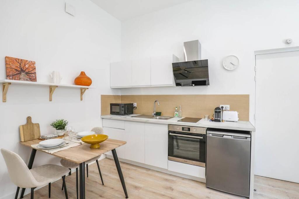 uma cozinha branca com uma mesa de madeira e uma sala de jantar em ®Le Cosy - Studio de charme em Marselha