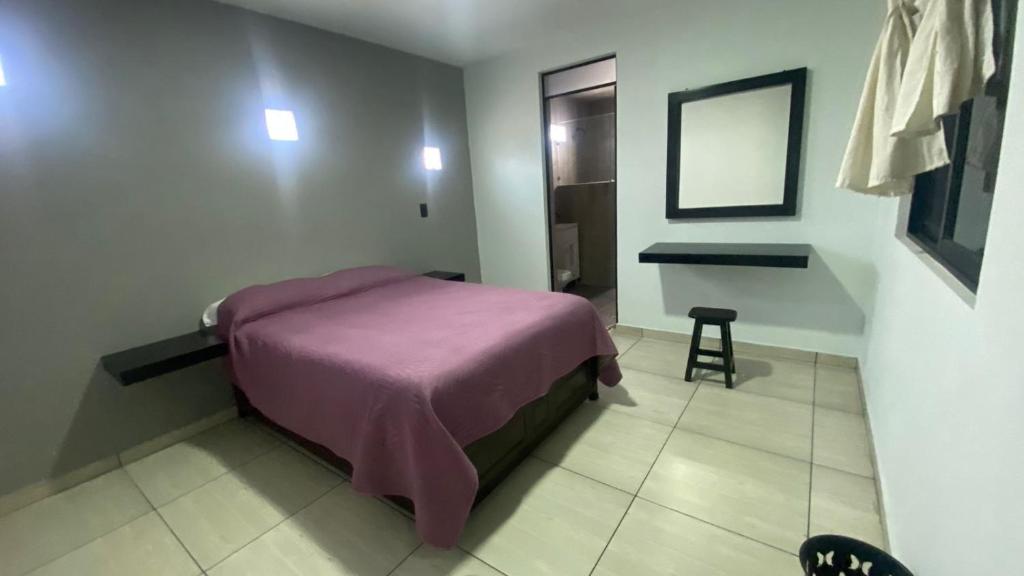 um pequeno quarto com uma cama roxa num quarto em Hotel posada Juquila em Zacatlán