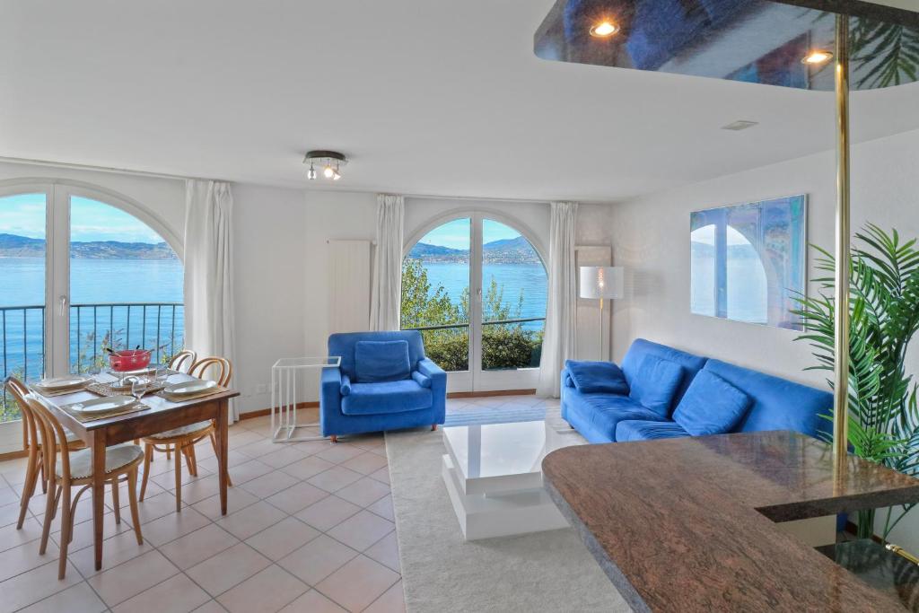 uma sala de estar com um sofá azul e uma mesa em Splendide logement avec vue plongeante sur le lac em Saint-Gingolph