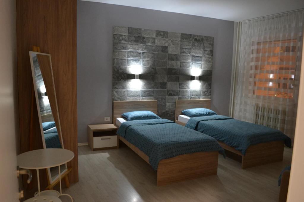 a bedroom with two beds and a table and a mirror at Lazarus Apartment in Skopje