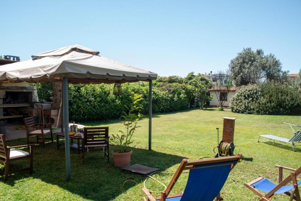 un patio con sillas, sombrilla y césped en Appartamento in Casa Olea, en SantʼAndrea