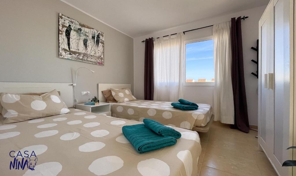 コラレホにあるLos Delfines Casa Nina by Rentalfueのベッド2台と窓が備わるホテルルームです。