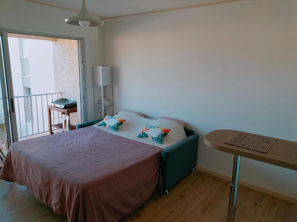 Un dormitorio con una cama con una mesa y un balcón. en Six Fours les Plages - Le Brusc - Studio vue mer, climatisé, en Six-Fours-les-Plages