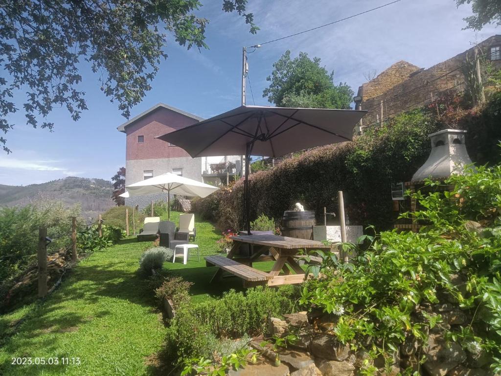 um jardim com uma mesa de piquenique e um guarda-sol em Cantinho do Préstimo em Águeda