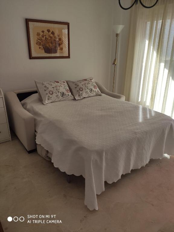 sypialnia z łóżkiem z białym kocem i oknem w obiekcie APARTAMENTO CASARES PLAYA w mieście San Luis de Sabinillas