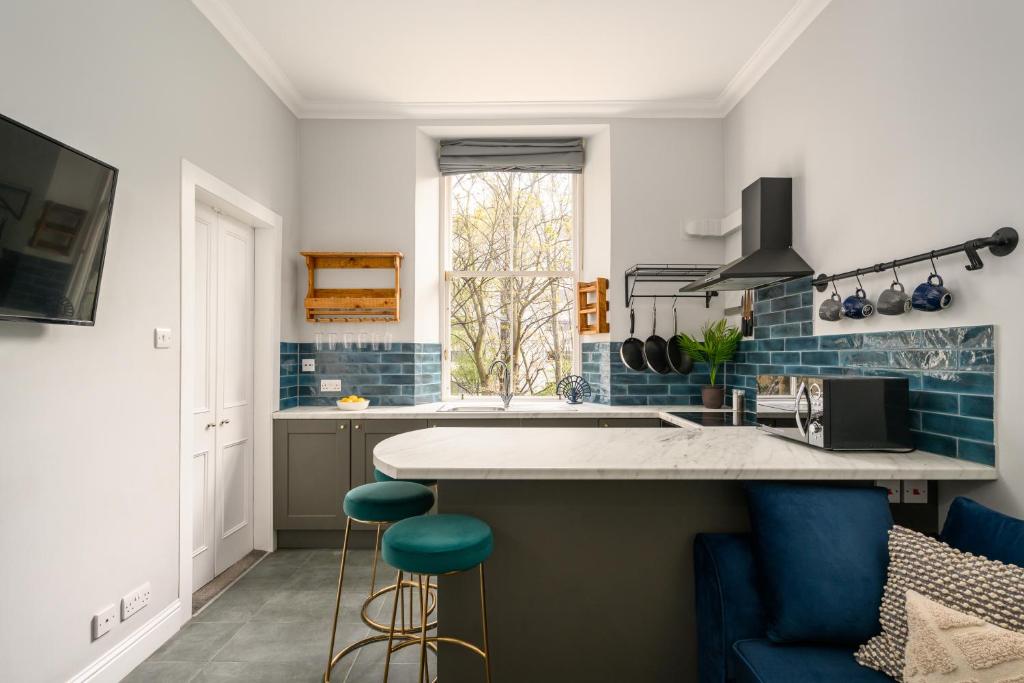 a kitchen with blue and white walls and a counter with stools at Vibrant Leith Flat in Edinburgh