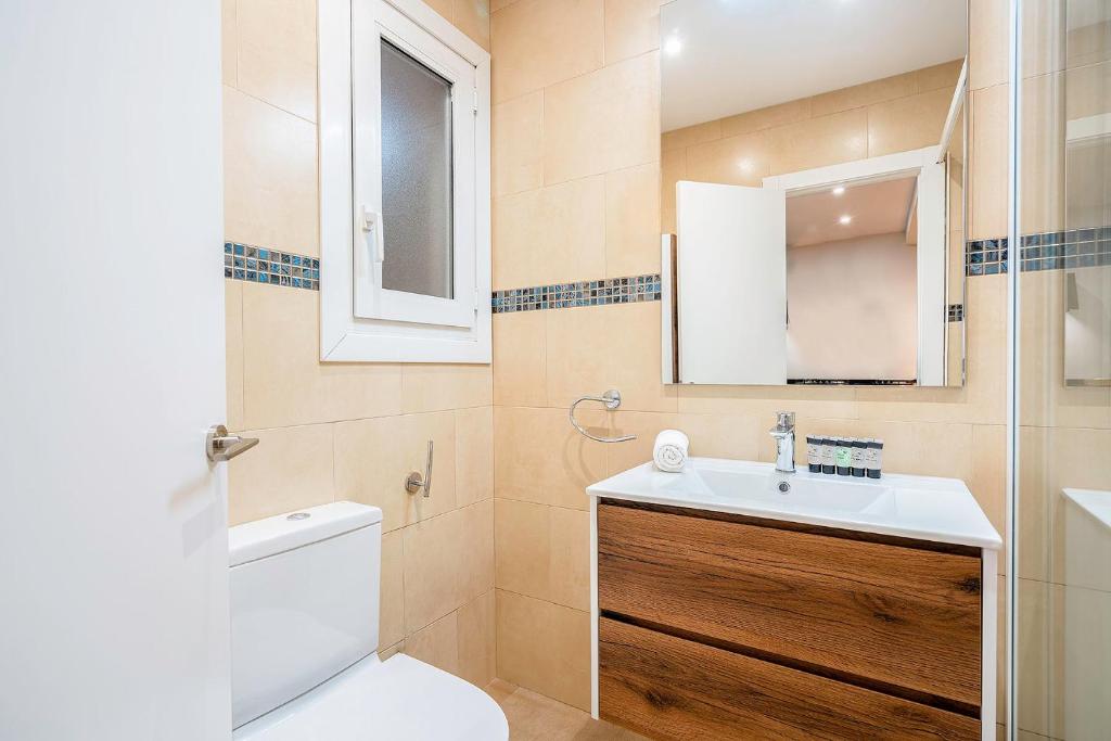 a bathroom with a toilet and a sink and a mirror at Barcelona Eixample in Barcelona