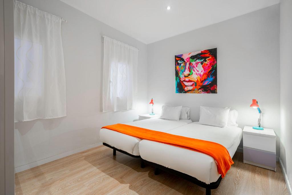 a white bedroom with a bed and a painting on the wall at Barcelona Eixample in Barcelona