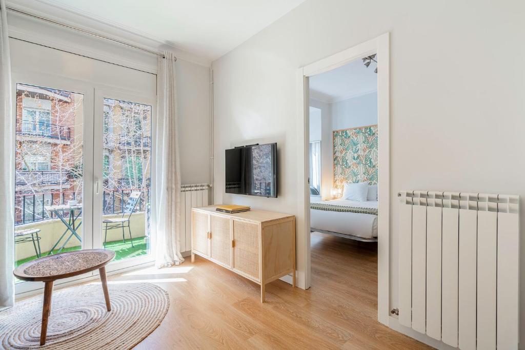 a white room with a television and a bedroom at Barcelona Eixample in Barcelona