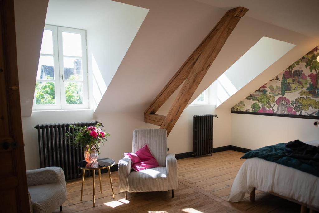 a attic room with a bed and a chair at Chez Agnès in Pont-lʼÉvêque