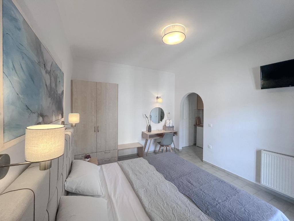 a white bedroom with a large bed and a desk at ATHANASIA APARTMENTS in Skiathos