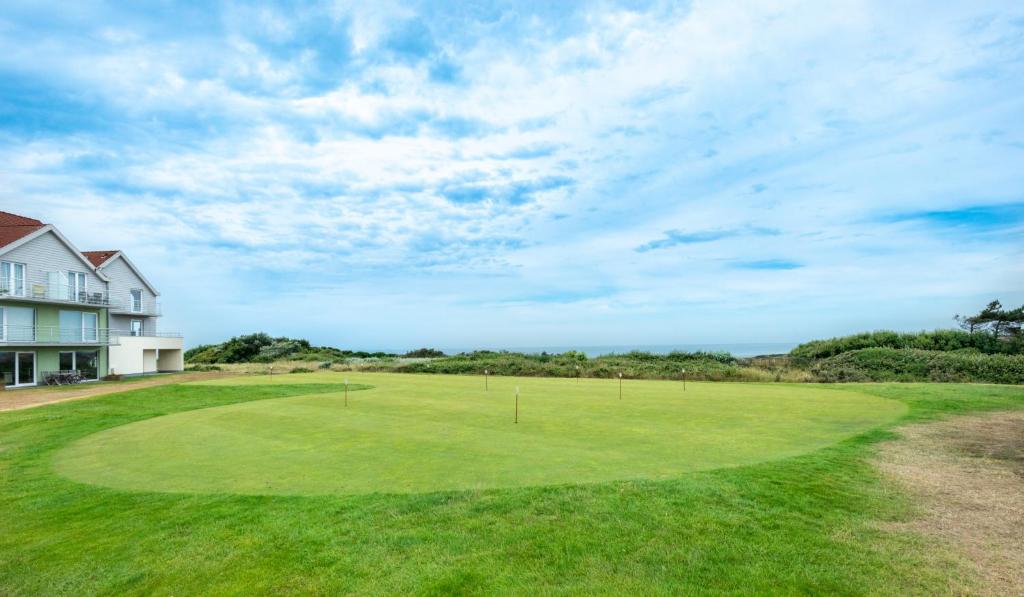 - une vue sur un parcours de golf avec une maison dans l'établissement Vue sur mer, dunes et golf, à Wimereux