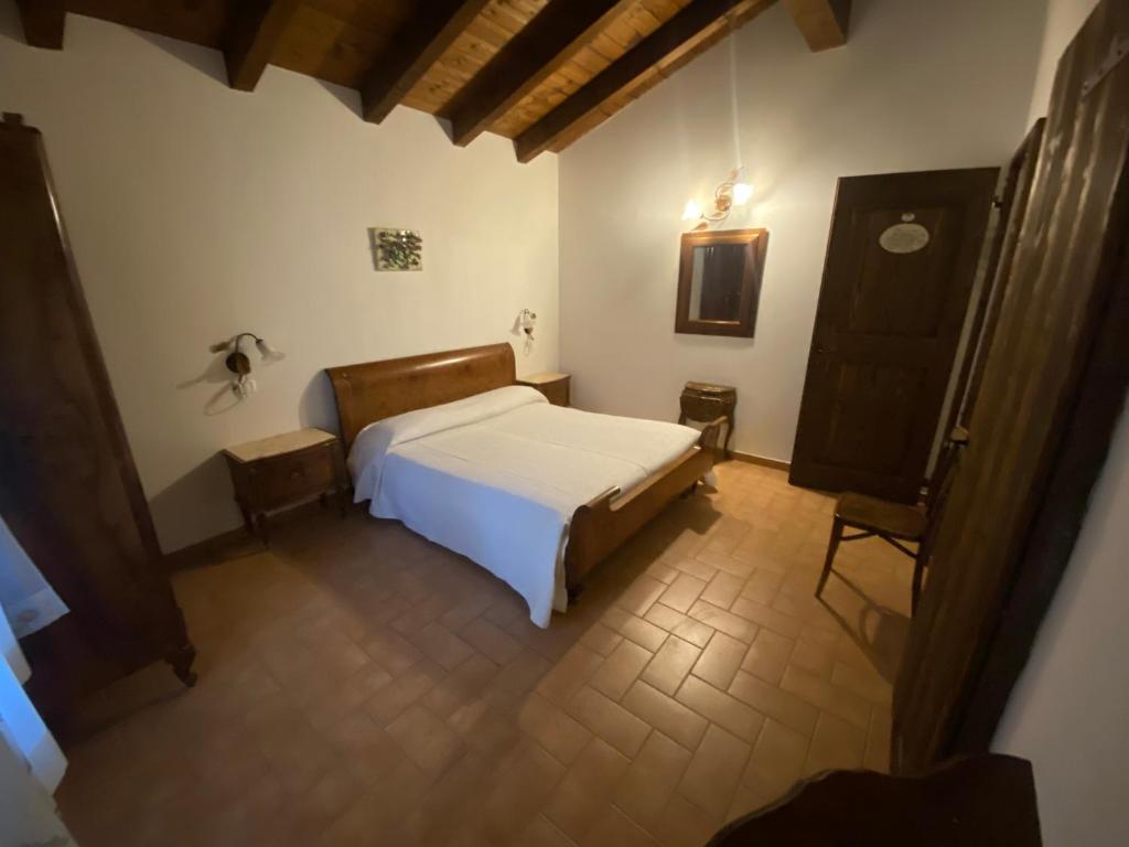 um quarto com uma cama branca e uma cadeira em Agriturismo Prunara Farmstead F.lli Santoli em Monzuno