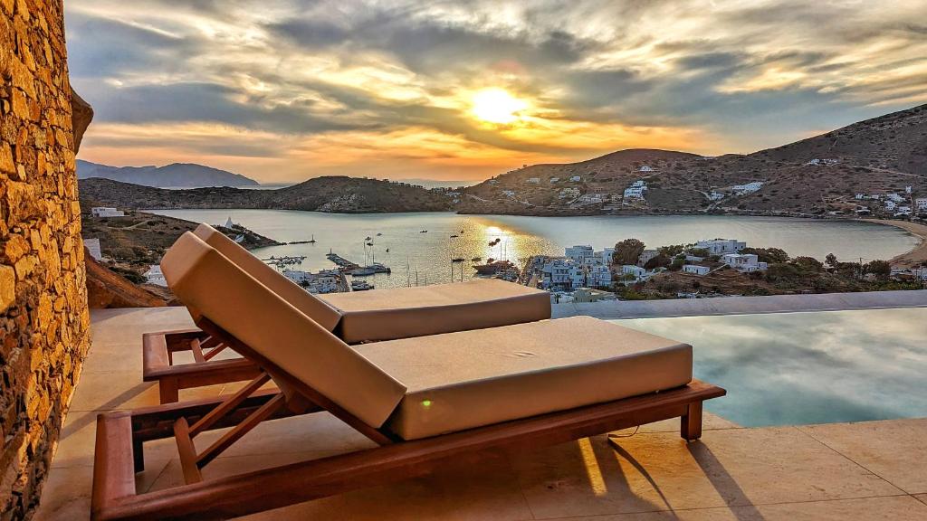 una silla en el balcón con vistas al agua en Villa Mirabilis, en Ios Chora