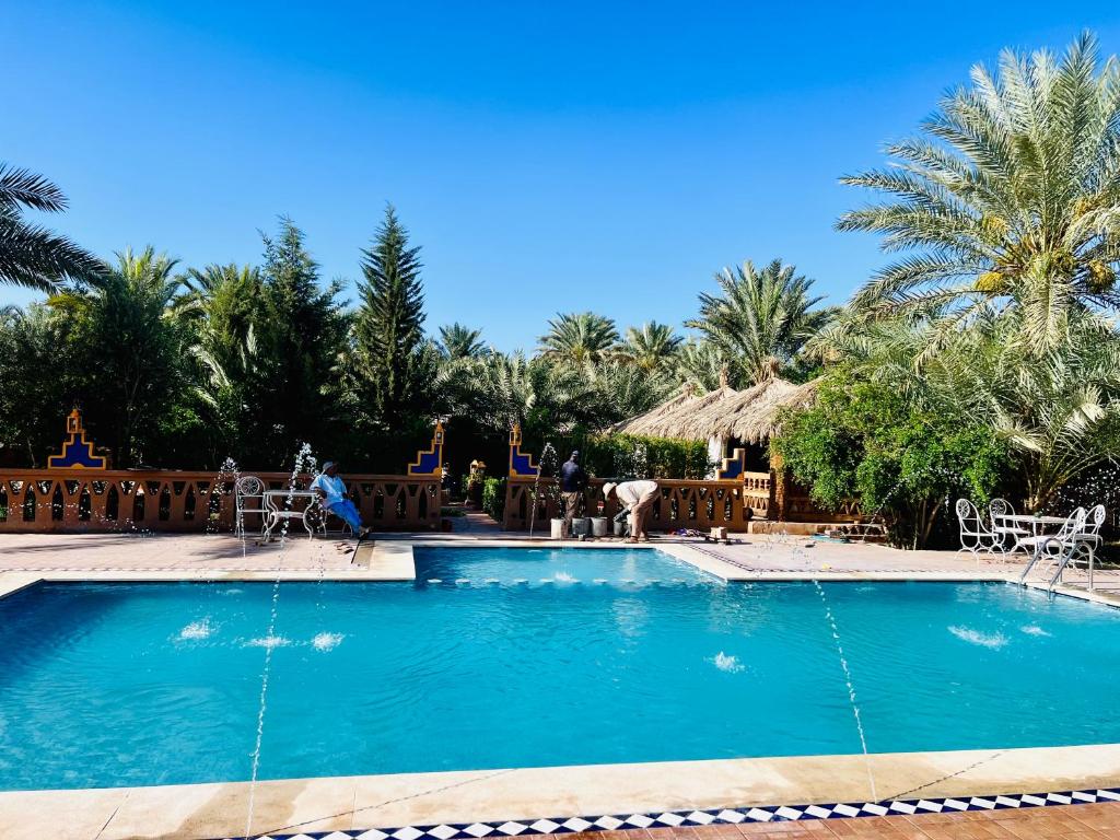 a swimming pool in a resort with palm trees at Paradis Touareg in Zagora