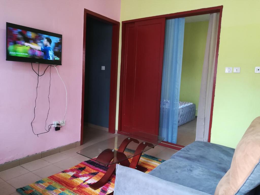 a living room with a tv on a wall at Studio meublé Yaoundé Centre ville in Yaoundé