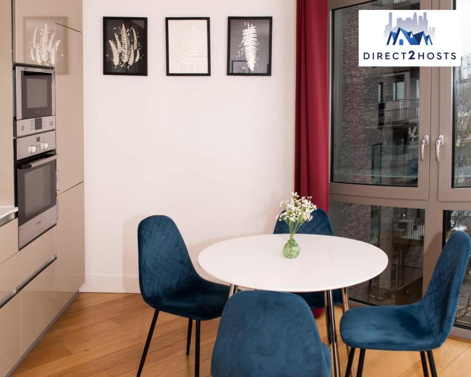 a dining room with a white table and blue chairs at Stylish & Comfy One Bedroom Apartment By Direct2hosts in Great East London location! in London