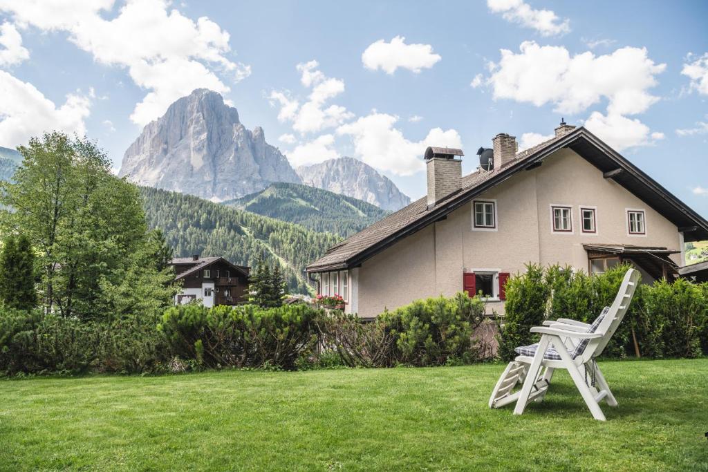 a white chair sitting in the grass in front of a house at Apartments Chalet Zirm in Santa Cristina in Val Gardena