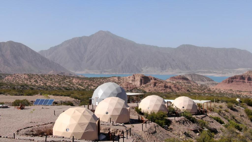 a group of four domes in a desert with mountains at Denmoza Eco Lodge in Potrerillos