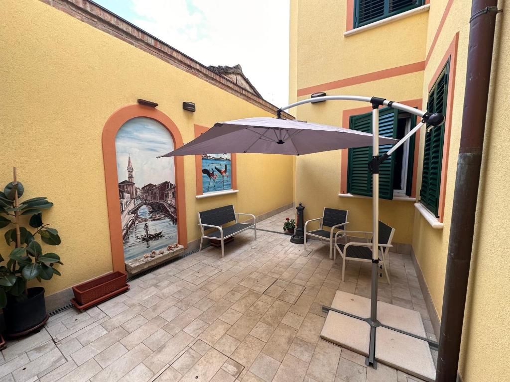 eine Terrasse mit einem Sonnenschirm und Stühlen sowie ein Gebäude in der Unterkunft IL FENICOTTERO in Comacchio