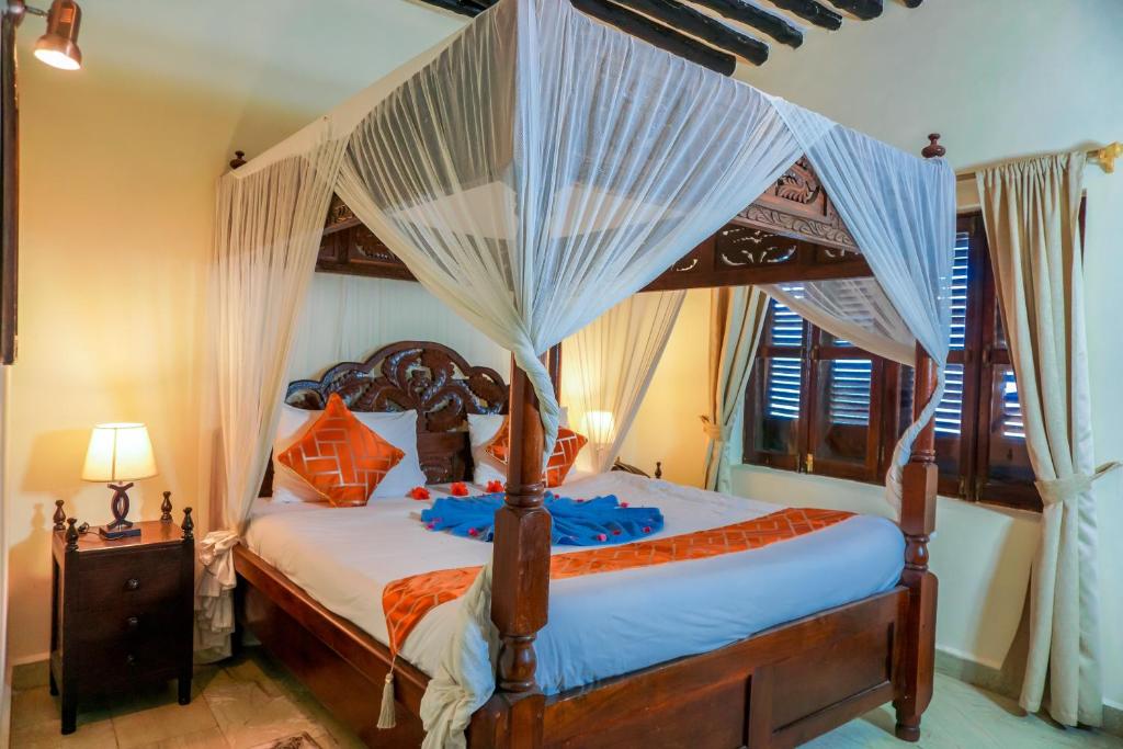 a bedroom with a canopy bed with mosquito netting at Al Johari Hotel & Spa in Zanzibar City