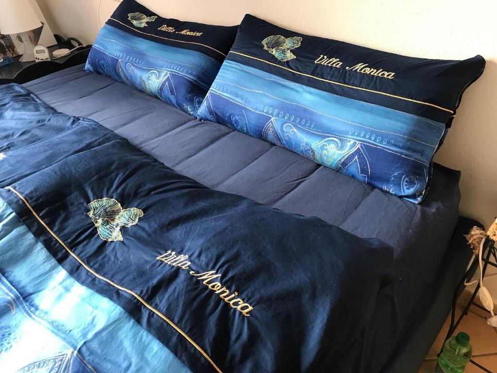 ein Bett mit blauer Bettwäsche und Kissen darauf in der Unterkunft Villa mit Whirlpool und phantastischer Aussicht in Capoliveri