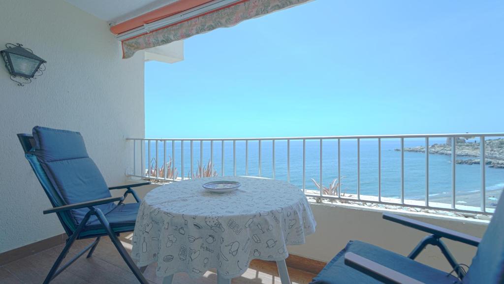 un tavolo e due sedie su un balcone con vista sull'oceano di Apartamento Brisa Del Mar ad Almuñécar