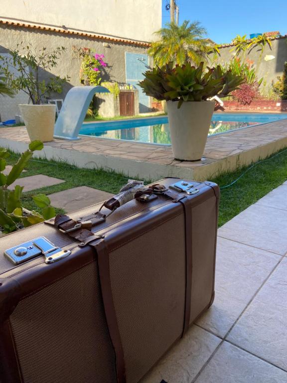 une valise assise sur un trottoir à côté d'une piscine dans l'établissement Suite cantinho do sossego, à Arraial do Cabo