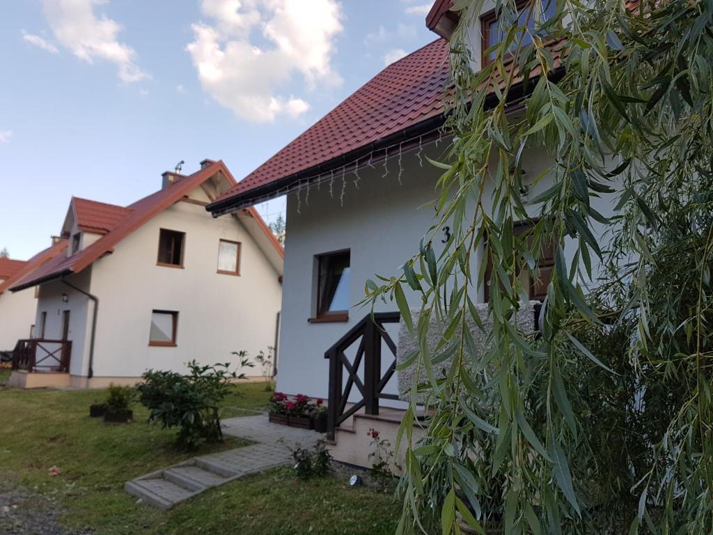 una casa blanca con un árbol al lado en Domki Oaza Spokoju Berezka, en Berezka