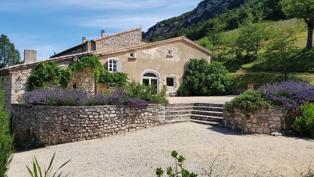una casa de piedra con una pared de piedra y flores púrpuras en Les Fonts de Baix, en Plan-de-Baix