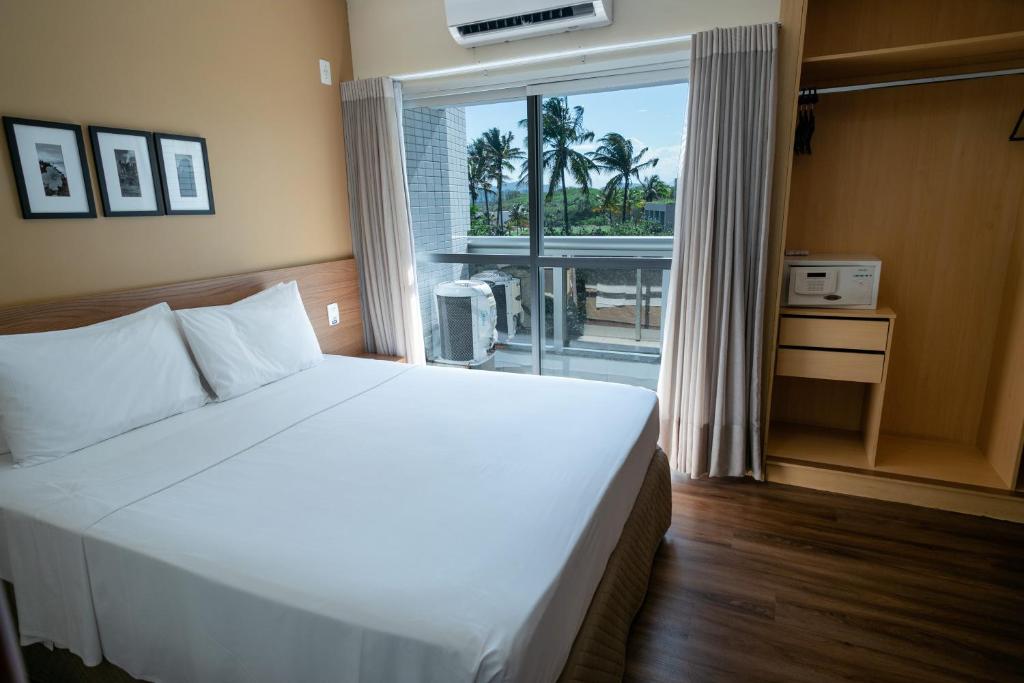 Un dormitorio con una gran cama blanca y una ventana en Nobile Suites Diamond en Vitória