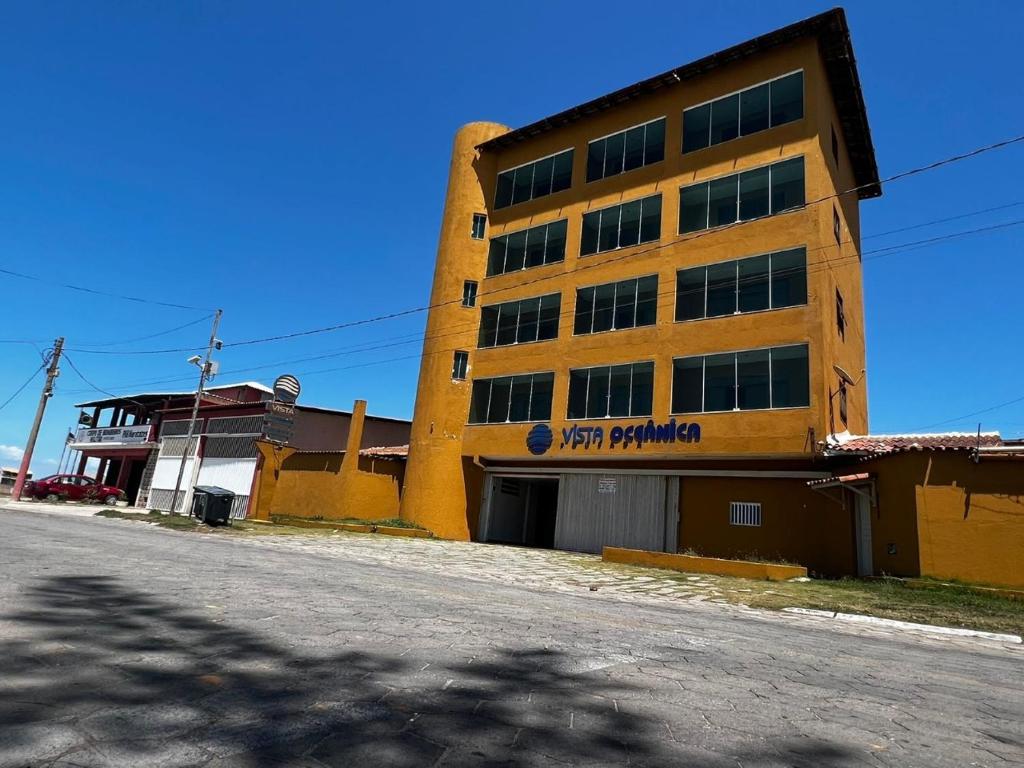 um grande edifício amarelo no lado de uma rua em Vista Oceanica Pousada em Marataízes