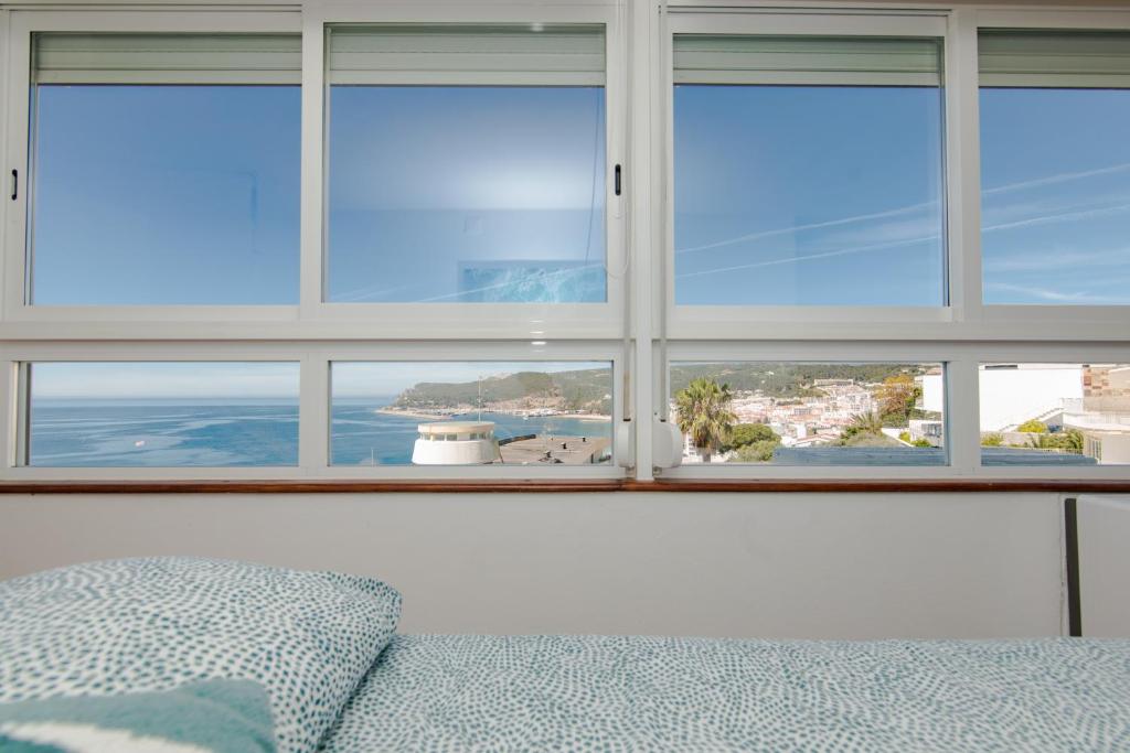 a bedroom with a window with views of the ocean at Sesimbra 1111 in Sesimbra